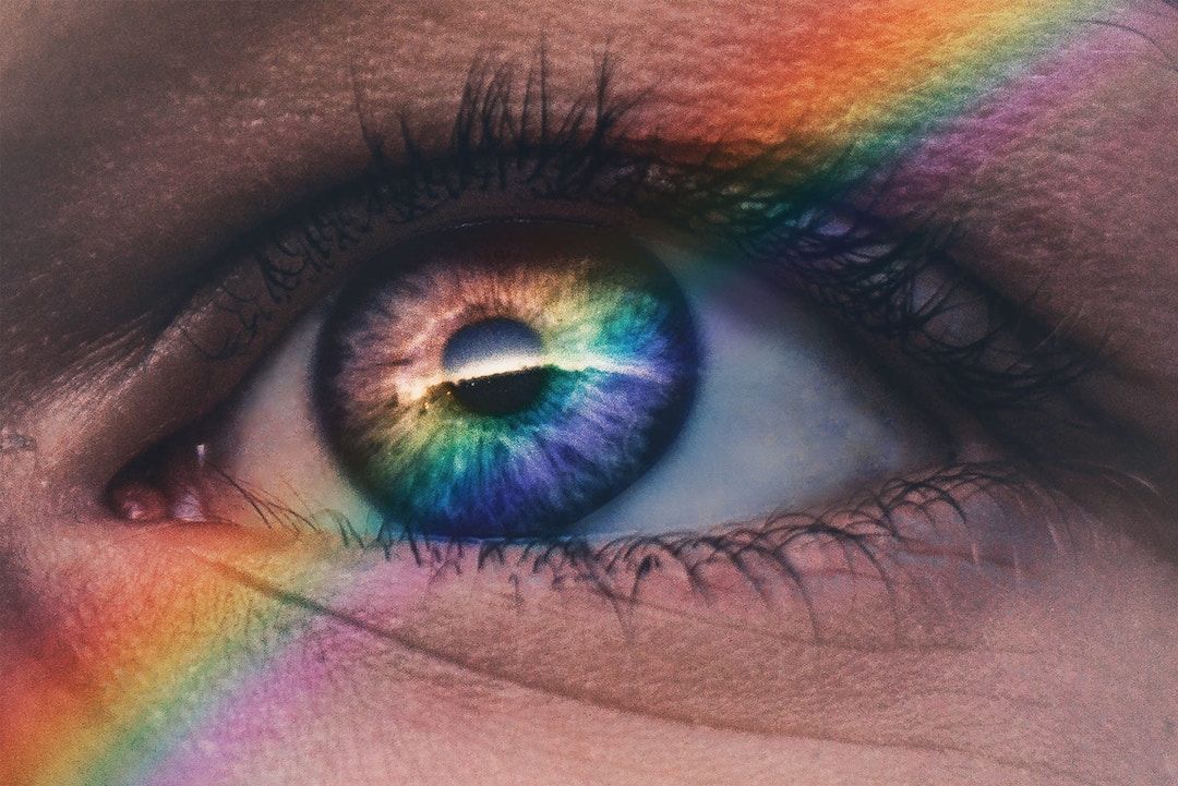 Psychedelic training programs. A close-up of an eye with a rainbow reflecting in the eye and across the person's face.