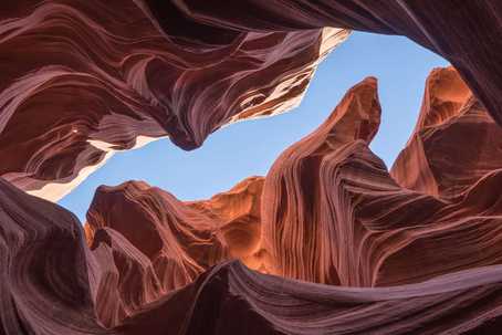 Challenging Psychedelic Experiences. Bottom-up view of a rocky cavern with flowy concentric psychedelic rock pattern. Some blue sky is visible in the crack between the rocks.